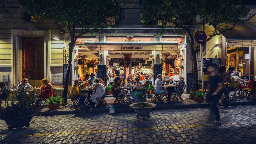 Seville, Spain - July 14th, 2018: Busy bar and restaurant on Calle Mateos Gago servicing Spanish style tapas to locals and tourists well into the late hours in the historic centre of Seville